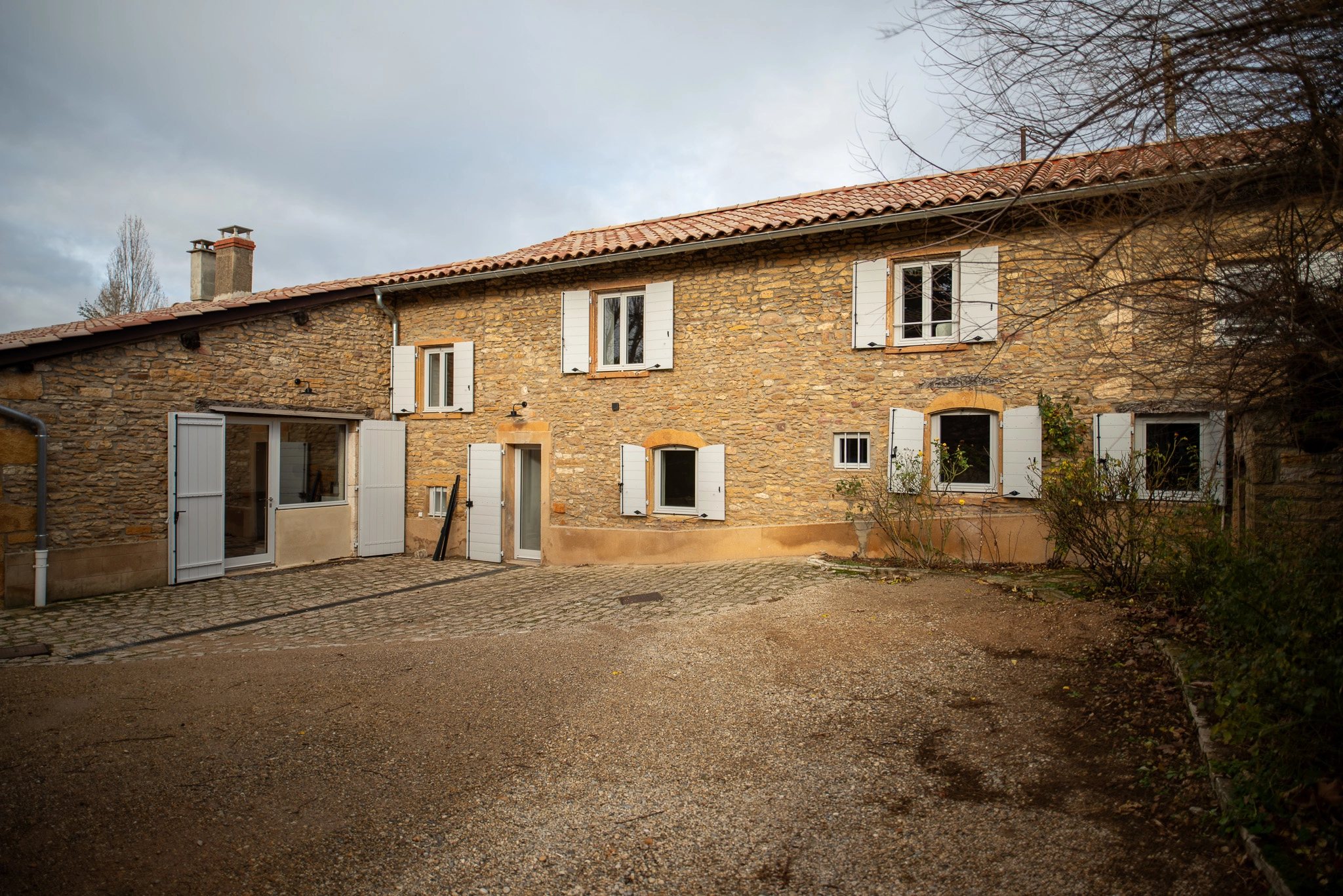 Volets en bois sur-mesure installés sur une façade en pierre à Lachassagne